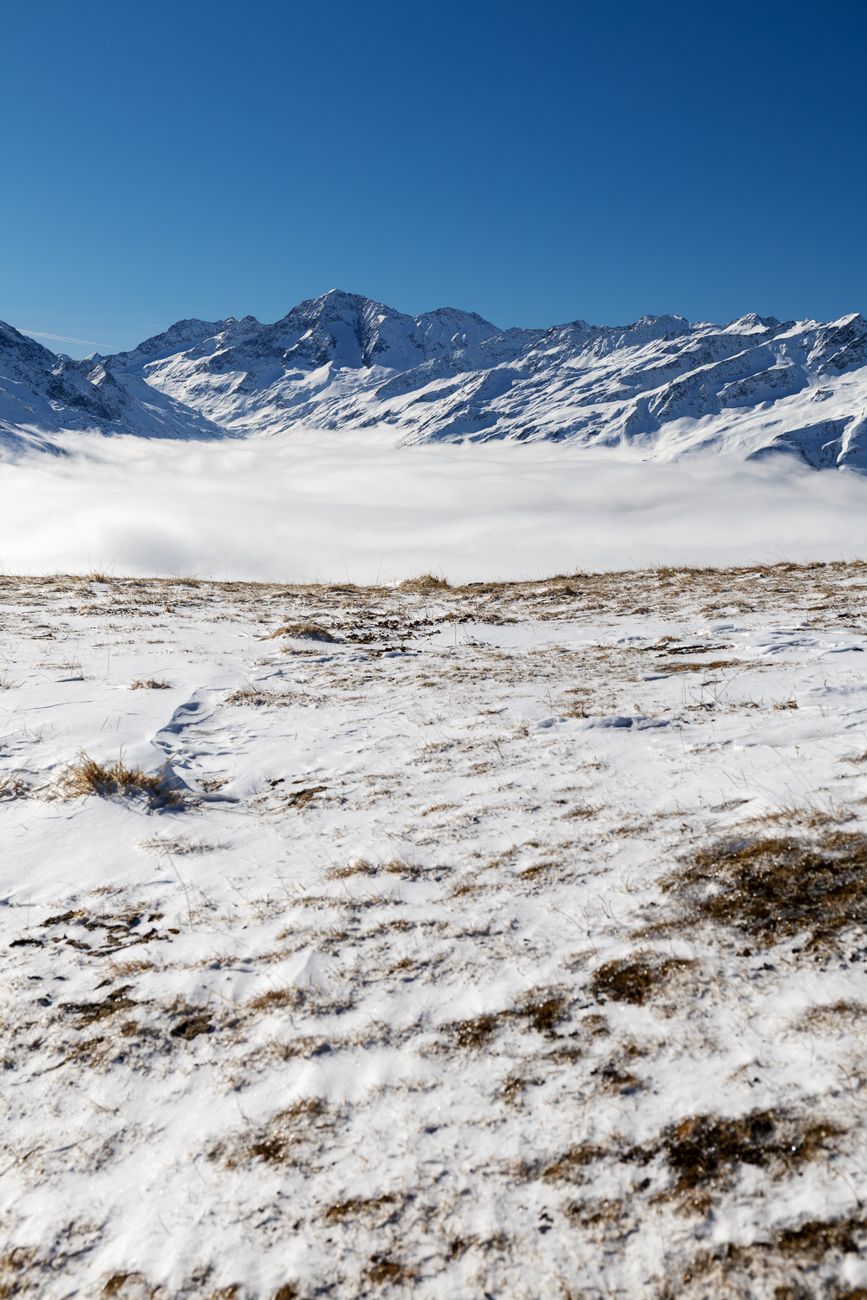 A breathtaking view of snow-covered mountains in Korutany, Austria under a clear blue sky.